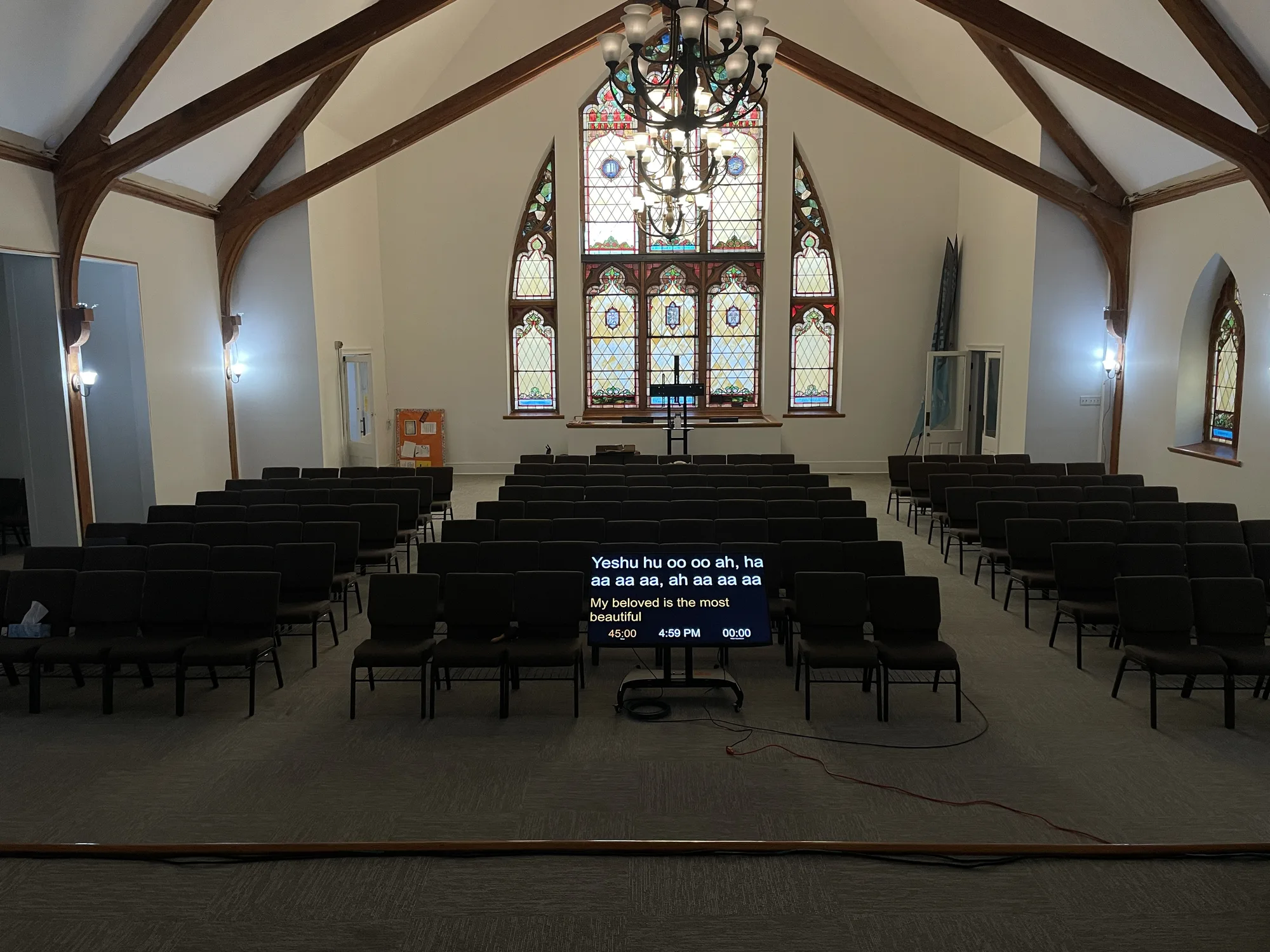 Rear sanctuary view showing a congregation display, stained glass windows, and the worship seating area