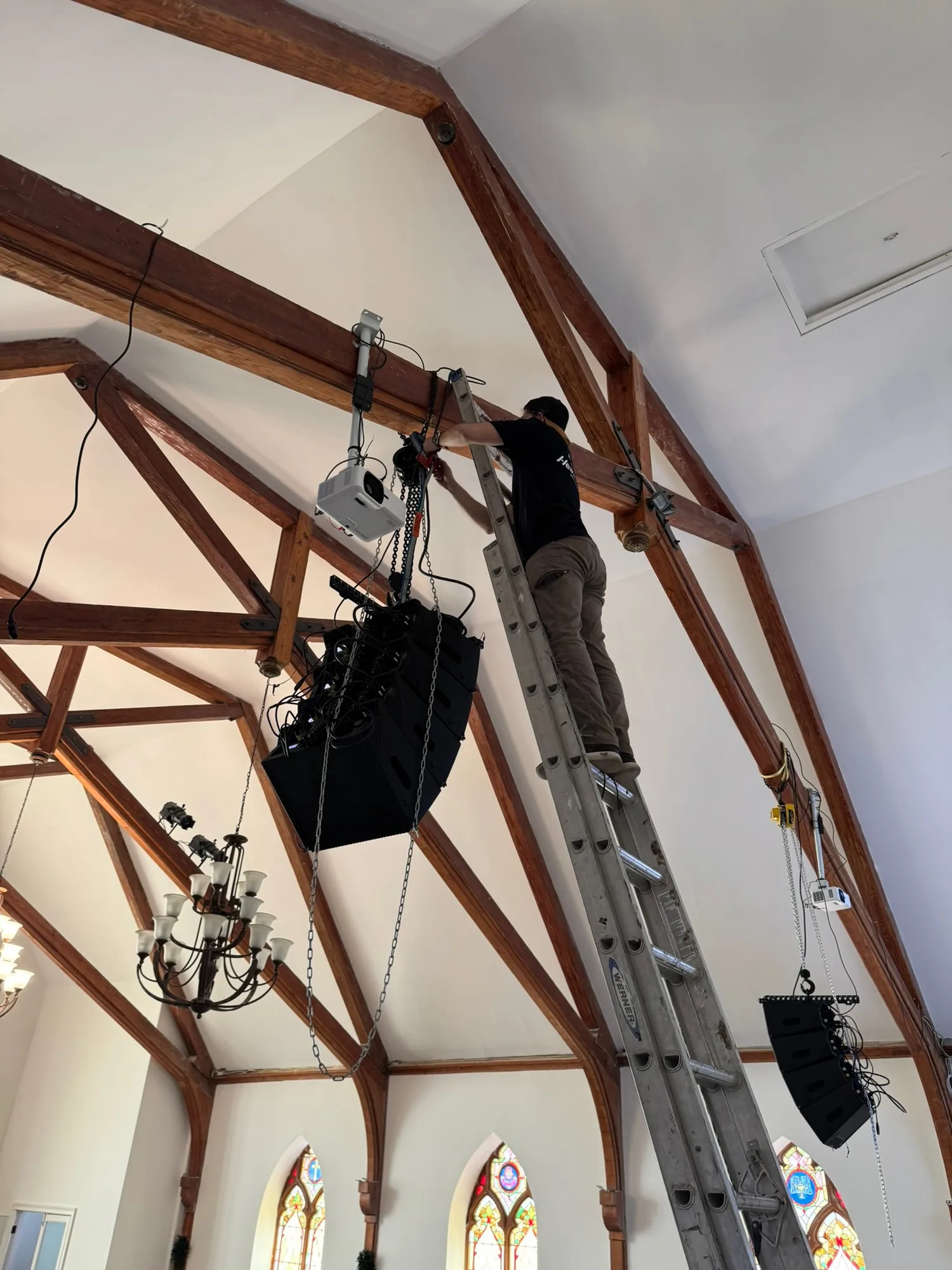 Suspended loudspeaker array and projector mounted within the exposed wood structure of The Way Church sanctuary