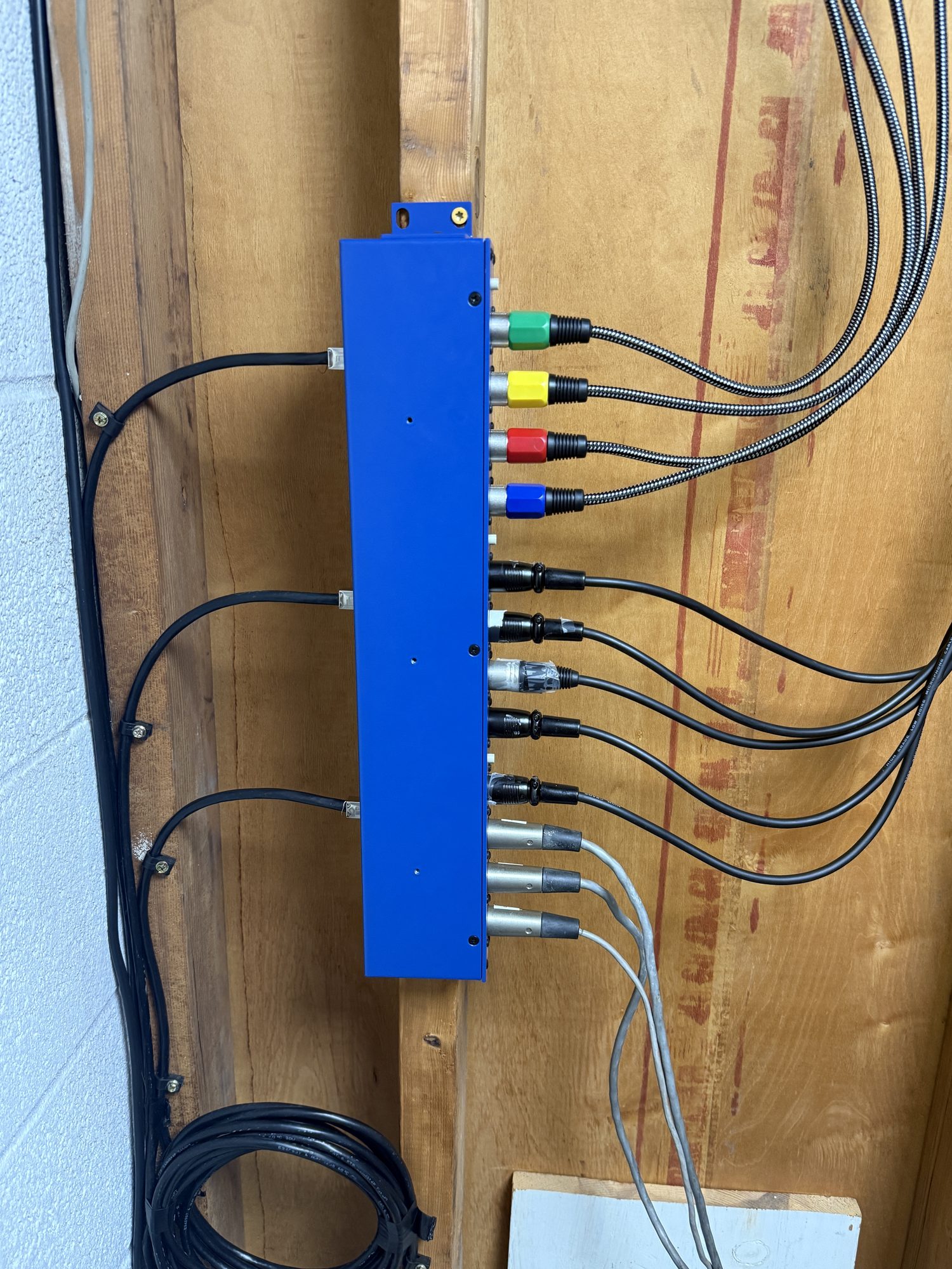 Close-up of organized A/V cabling and connectors on a blue termination panel