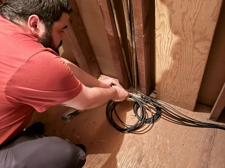 Technician routing and securing A/V cable inside the church structure