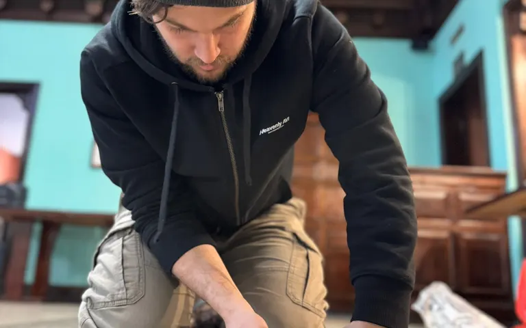 Technician kneeling and securing rigging hardware on the floor inside the worship space