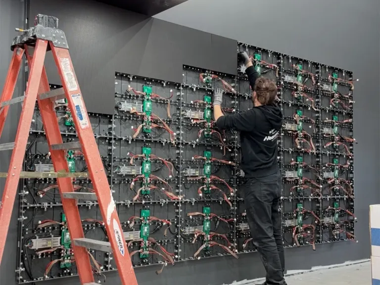 Technician wiring LED wall panels during installation in the church worship space