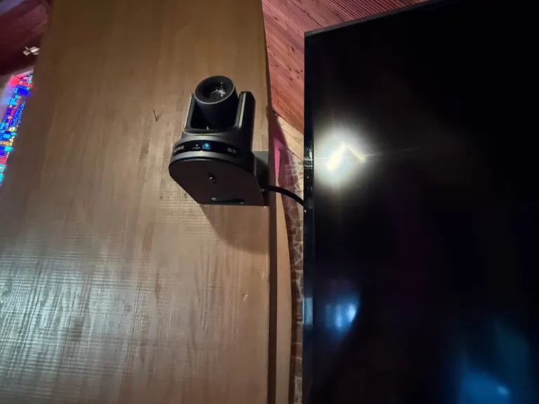 Mounted PTZ camera beside a wall display in the church sanctuary