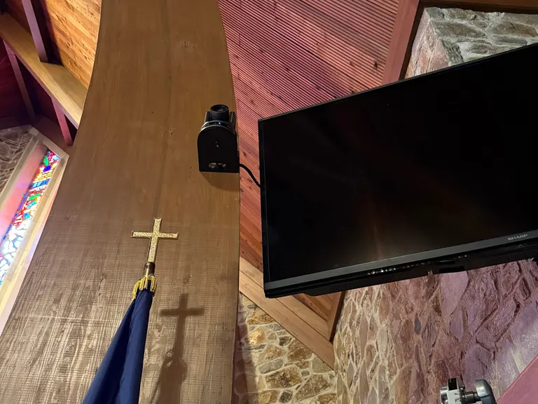PTZ camera mounted high on a sanctuary column near a wall display