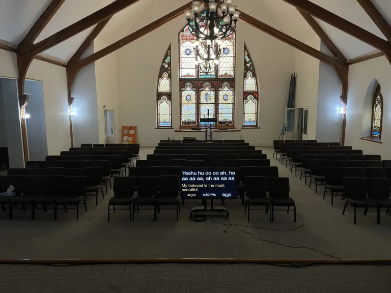 Rear sanctuary view showing a congregation display, stained glass windows, and the worship seating area