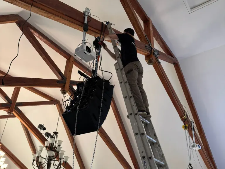 Suspended loudspeaker array and projector mounted within the exposed wood structure of The Way Church sanctuary