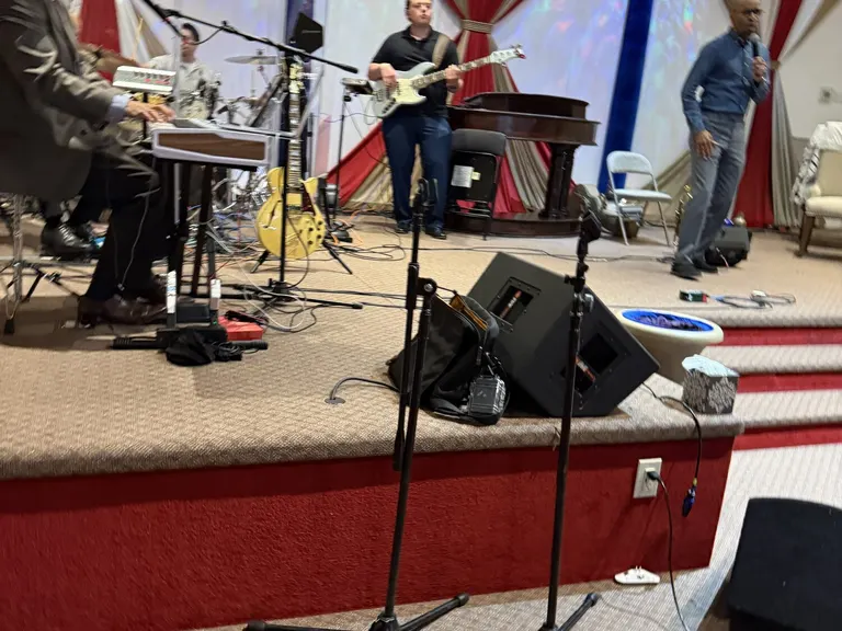 Worship band performing on the convention stage with microphones, instruments, and stage monitors