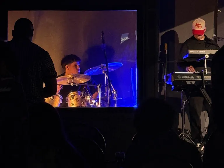 Drummer in a drum enclosure and keyboard player during a church worship service