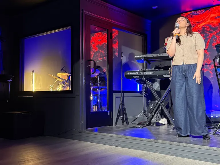 Singer beside a keyboard setup on a church stage with colored lighting and LED visuals